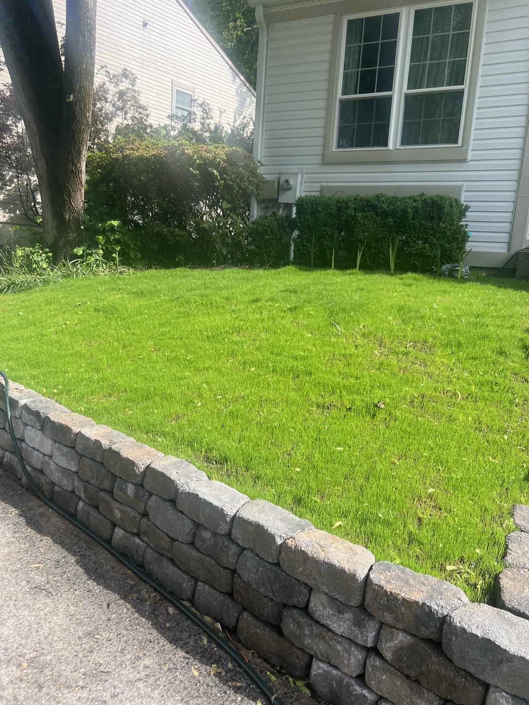 Finished stacked-stone retaining wall with a lush green lawn behind it